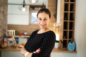 Waist up portrait of one adult caucasian woman beautiful millennial female standing in the kitchen at home copy space looking to the camera smiling happy confident real people