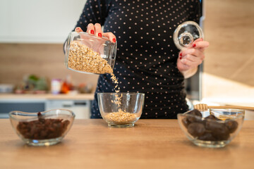 Close up on hands of unknown caucasian woman preparing healthy breakfast oatmeal at home