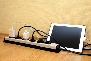 The electrical extension strip with connected power plugs. Tablet computer with black screen. space for text.