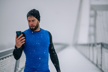 Man using smartphone while training outside on the snow.