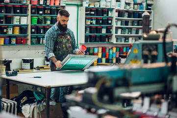 Male worker mixing colors for screen printing in a workshop