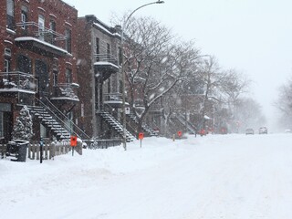 Cars on the snowy road during a huge snowfall and blizzard in Montreal, Canada, in Mile End neighborhood on Plateau Mont Royal. No traffic, street is almost empty.