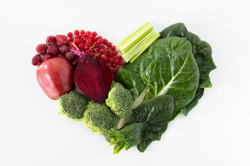 Creative heart shape from various fresh red and green vegetables and fruits isolated on white...