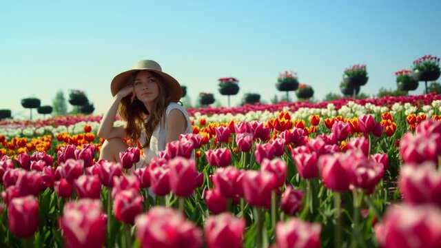 Relaxed woman sitting in beautiful spring garden. View of blooming tulip field. 