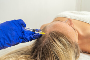Mesotherapy procedure. A cosmetologist does a mesotherapy procedure in a woman's head....