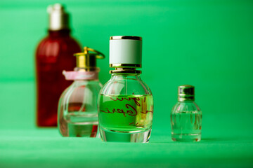 Different bottles of eau de toilette perfumes fragrances on green background. Cosmetic essential oil in bottles, jars. Cosmetics for beauty care. Set of vials, aroma oils for aromatherapy. Body Lotion