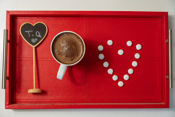 A fabulous red breakfast tray with a glass of cocoa and sweet chocolates