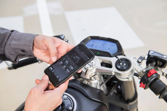 technician checking electric motorcycle with smartphone at workshop