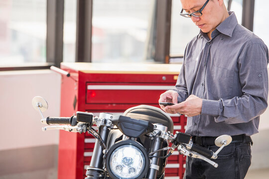 technician checking electric motorcycle with smartphone at workshop