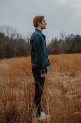 Man standing in field looking into the distance thinking about life, mens fashion 