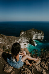 A young travelling and backpacking girl visits Kelingking Beach in Nusa Penida, Indonesia....