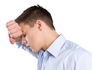 Depressed young man with fist clenched leaning his head against a wall