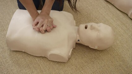 Woman's hands practicing chest compression on dummy in first aid EMT training