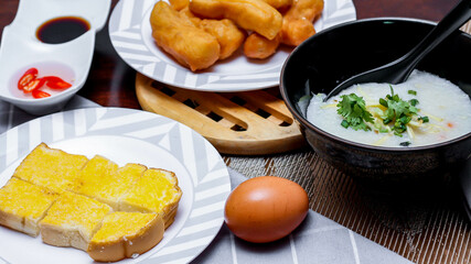 Chinese style porridge or porridge and fried dough stick or fried dough stick or donut or fried bread placed on a brown wooden table. Thai street food called 