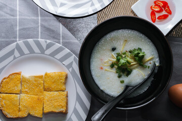 Chinese style porridge or porridge and fried dough stick or fried dough stick or donut or fried bread placed on a brown wooden table. Thai street food called 