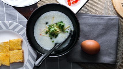 Chinese style porridge or porridge and fried dough stick or fried dough stick or donut or fried bread placed on a brown wooden table. Thai street food called 