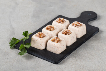 Buckwheat cream jelly in the form of square savarin on a serving board on a light gray background
