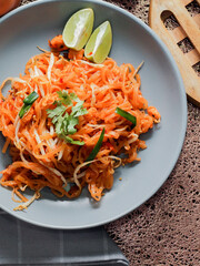 Thai Food Pad Thai (Thai national dish) Pad Thai on a gray plate with lime and garnishes.