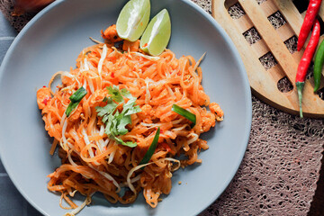 Thai Food Pad Thai (Thai national dish) Pad Thai on a gray plate with lime and garnishes.