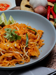 Thai Food Pad Thai (Thai national dish) Pad Thai on a gray plate with lime and garnishes.