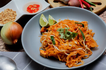 Thai Food Pad Thai (Thai national dish) Pad Thai on a gray plate with lime and garnishes.