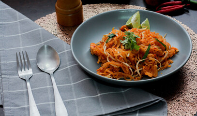Thai Food Pad Thai (Thai national dish) Pad Thai on a gray plate with lime and garnishes.