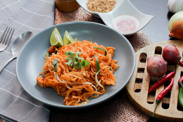 Thai Food Pad Thai (Thai national dish) Pad Thai on a gray plate with lime and garnishes.
