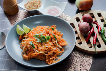 Thai Food Pad Thai (Thai national dish) Pad Thai on a gray plate with lime and garnishes.