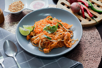 Thai Food Pad Thai (Thai national dish) Pad Thai on a gray plate with lime and garnishes.