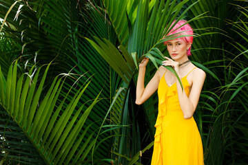 Fashion Poses of Pink dying hair woman wear yellow dress and look strong over tropical green leaves