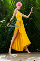 Fashion Poses of Pink dying hair woman wear yellow dress and look strong over tropical green leaves