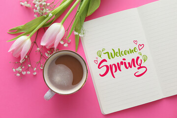 Notebook with text WELCOME SPRING, beautiful flowers and cup of coffee on pink background