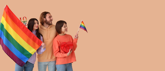 Man and two beautiful women with rainbow flags and gift on color background with space for text. Concept of polyamory and LGBT