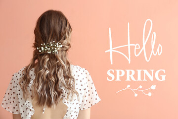 Pretty young woman with flowers in her hair and text HELLO SPRING on color background