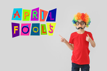Little boy in funny disguise on light background. April Fool's Day celebration