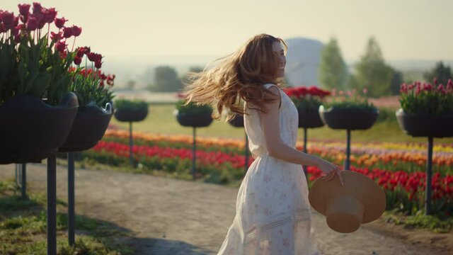 Pretty girl jumping with lightness and elegance in spring flower garden outside.