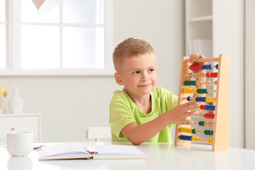 Adorable little boy learning math with abacus at home