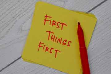 First Things First write on sticky notes isolated on Wooden Table.