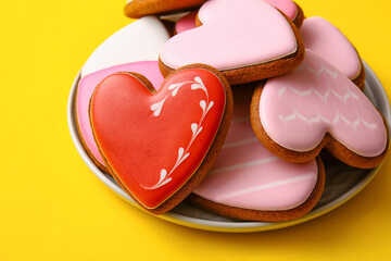 Plate with tasty heart shaped cookies on yellow background, closeup