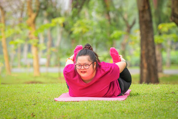 young woman with down syndrome or autism doing yoga outdoors