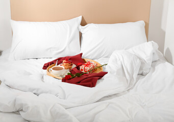 Wooden tray with breakfast, rose and gift for Valentine's Day on bed