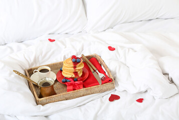Fototapeta na wymiar Tray with delicious breakfast and gift for Valentine's Day on bed