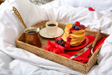 Tray with delicious breakfast and gift for Valentine's Day on soft bed