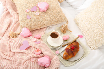 Tray with delicious breakfast and hearts on bed