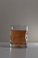 Simple clear glass with bubbly liquid on a white background. Small indent on the bottom on the glass. 
