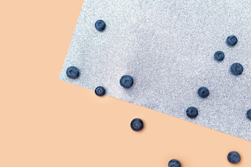 scattered blueberry berries on a beige and gray shiny background. close-up