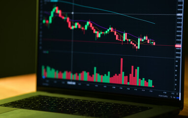 Cryptocurrency coin price evolution. A trader is viewing the graph on the crypto exchange stock market through a laptop screen.