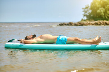 A man in blue swim wear lying on a kaya and sunbathing