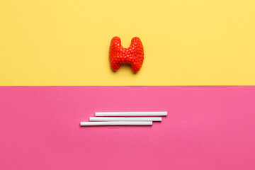 Thyroid gland and cigarettes on color background. Concept of balance