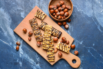 Board with tasty chocolate nut bars on color background